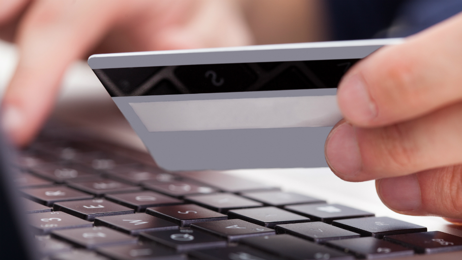 Pessoa digita dados do cartão de crédito em compra online