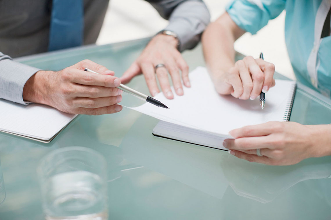 Mãos de duas pessoas em situação de negócios fazem anotações sobre a mesa
