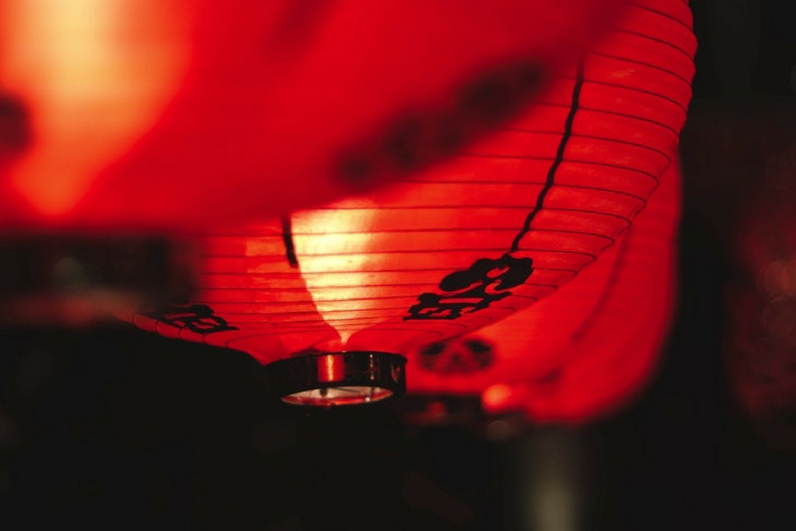 Luminária vermelha com letra chinesa estampada.