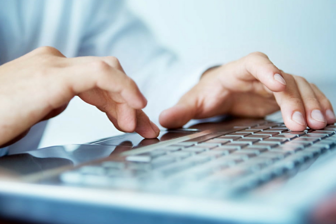 Mãos brancas teclam em um computador em close up, representando distração com a internet