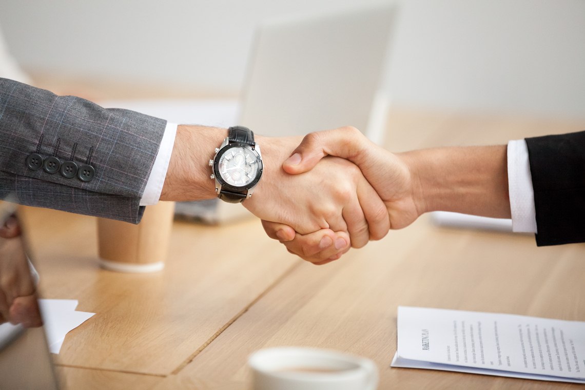 Fusões e Aquisições Closeup view of handshake, two businessmen in suits shaking hand Fusões e Aquisições