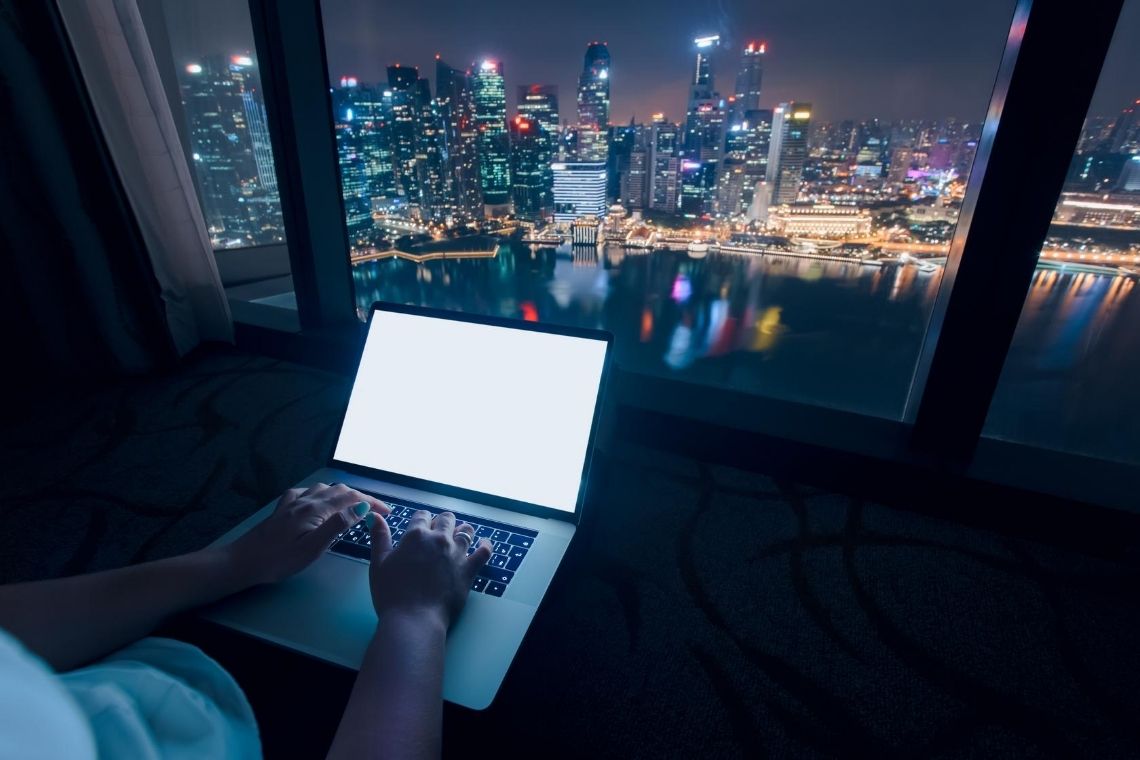 pessoa trabalhando em computador com vista para uma cidade à noite
