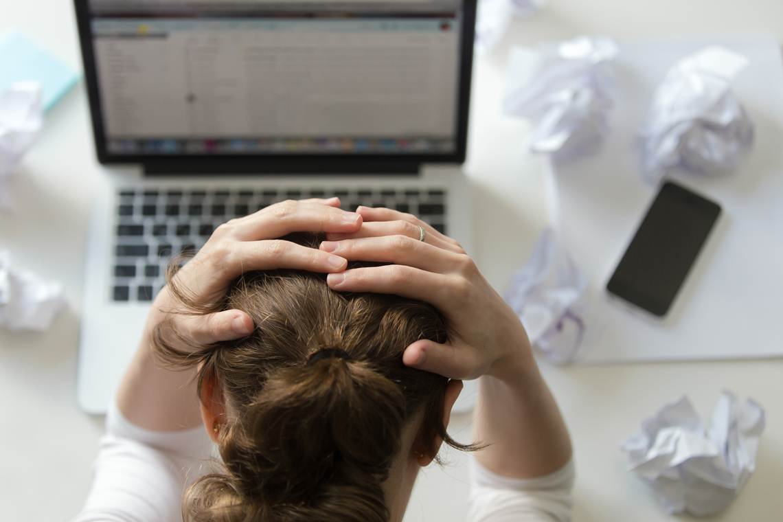 Portrait of a woman grabbing head at desk near the laptop trauma na pandemia