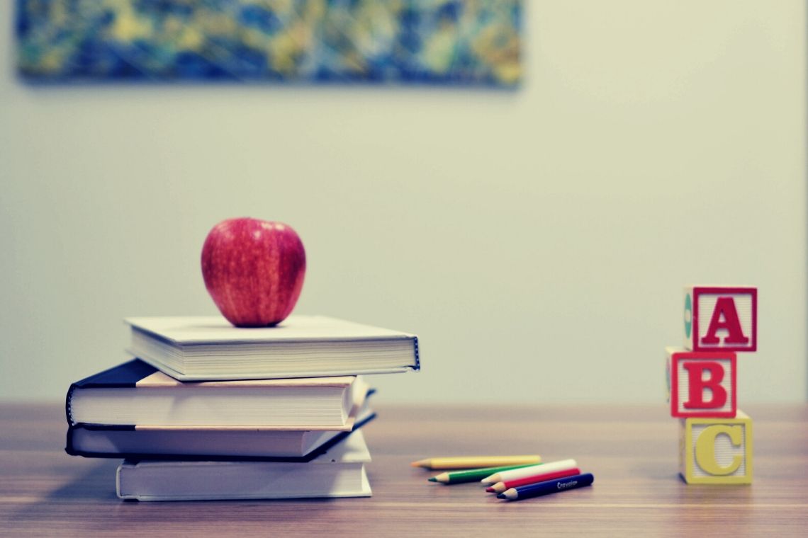 foto de maçã em cima de livro, lápis e dados com letras simbolizando estilos diferentes de aprendizado