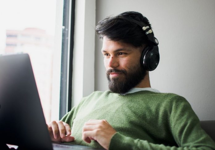 homem assistindo algo no computador, de fone de ouvido