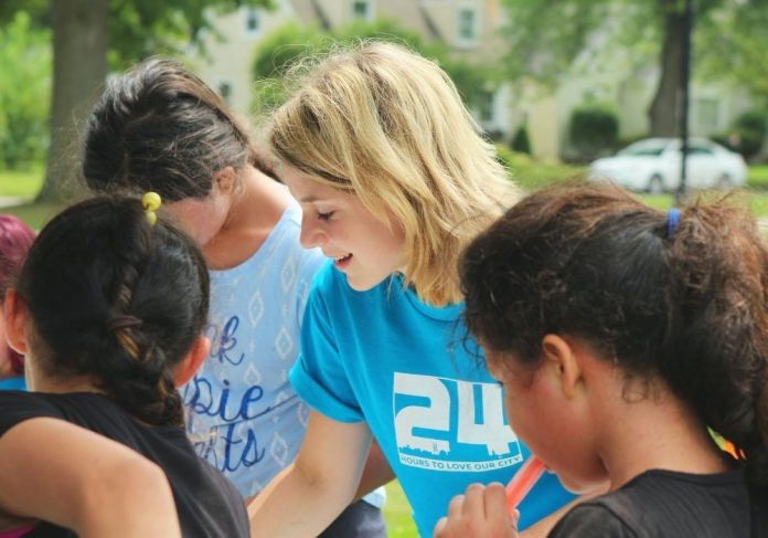 trabalho voluntário: no centro da imagem, uma jovem auxilia crianças mais jovens em uma atividade lúdica