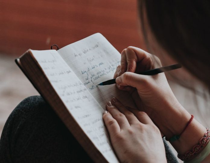 Uma mulher escreve um bloco de notas, tentando aprender como decorar um texto