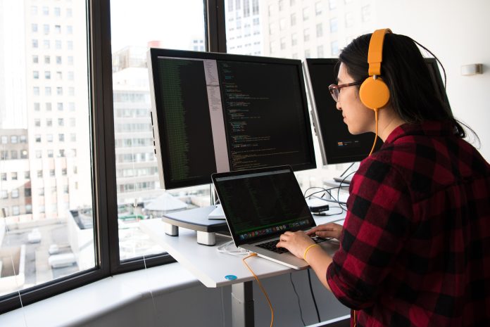 Mulher com fones de ouvido sentada em frente a um computador